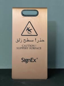 a copper plated board sign and caution slippery surface and signex name written in a Wayfinding sign in Riyadh by signex