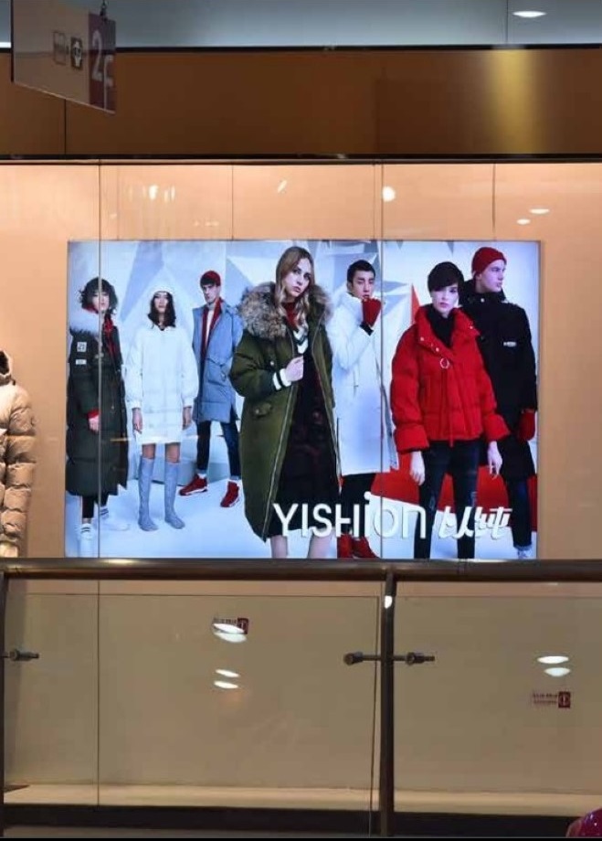 seven boys and girls are standing ina signage in a white themed background and it shows in a digital screen