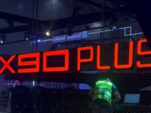 orange colored signages in a exhibition room and X90 PLUS written on the signages